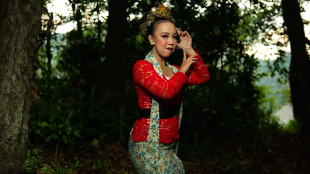 a Balinese dancer wearing a red costume which becomes a visual attraction for the audience with the beauty of the dance performed in the forest in the afternoon