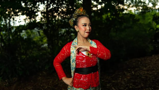 a traditional Balinese dancer wearing a red costume which is a symbol of cultural preservation with beautiful motifs while in the forest in the morning