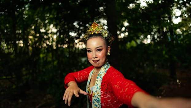 a traditional Balinese dancer wearing a red costume which is a symbol of cultural preservation with beautiful motifs while in the forest in the morning