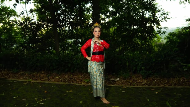 a traditional Balinese dancer wearing a red costume which is a symbol of cultural preservation with beautiful motifs while in the forest in the morning