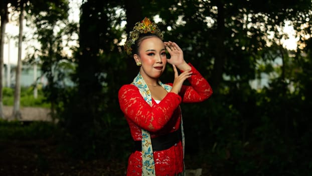 a traditional Balinese dancer wearing a red costume which is a symbol of cultural preservation with beautiful motifs while in the forest in the morning