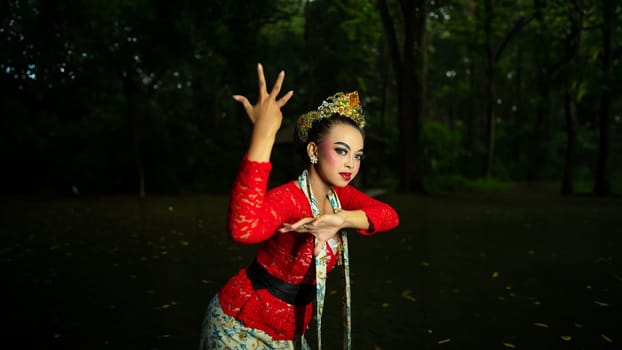 a Balinese dancer wearing a red costume which becomes a visual attraction for the audience with the beauty of the dance performed in the forest in the afternoon