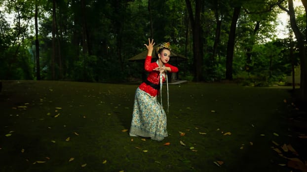 a Balinese dancer wearing a red costume which becomes a visual attraction for the audience with the beauty of the dance performed in the forest in the afternoon