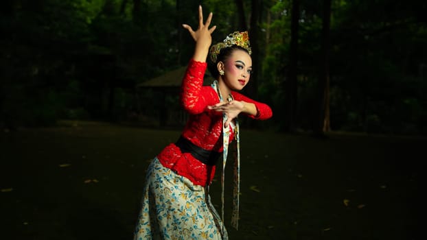 a Balinese dancer wearing a red costume which becomes a visual attraction for the audience with the beauty of the dance performed in the forest in the afternoon