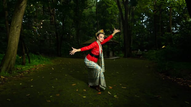 a Balinese dancer wearing a red costume which becomes a visual attraction for the audience with the beauty of the dance performed in the forest in the afternoon
