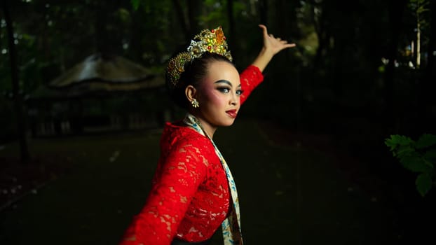 A traditional Javanese dancer wears jewelry on a red costume such as bracelets and necklaces to add to the impression of luxury when dancing in the forest in the morning