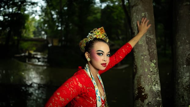 A traditional Javanese dancer wears jewelry on a red costume such as bracelets and necklaces to add to the impression of luxury when dancing in the forest in the morning