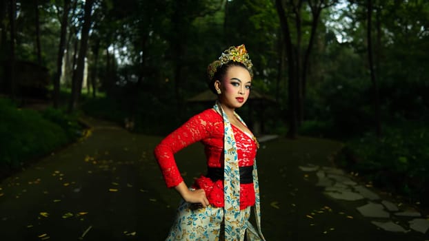 A traditional Javanese dancer wears jewelry on a red costume such as bracelets and necklaces to add to the impression of luxury when dancing in the forest in the morning