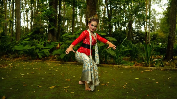 a traditional Sundanese dancer wearing a red costume that reflects the beauty and richness of Indonesian culture while in the forest in the morning