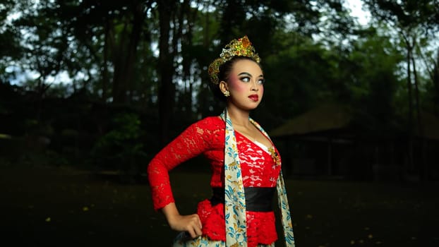 A traditional Javanese dancer wears jewelry on a red costume such as bracelets and necklaces to add to the impression of luxury when dancing in the forest in the morning