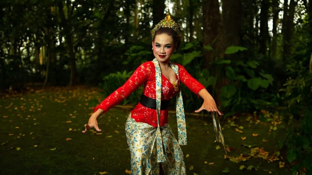 a traditional Sundanese dancer wearing a red costume that reflects the beauty and richness of Indonesian culture while in the forest in the morning