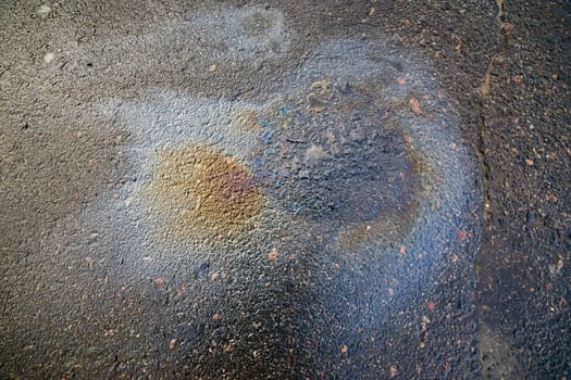 Brightly colored oil stain forming an abstract pattern on asphalt
