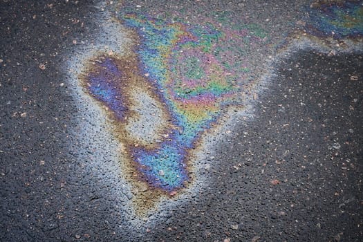 Asphalt oil stain, bright gasoline spots on the road surface as a texture or background.