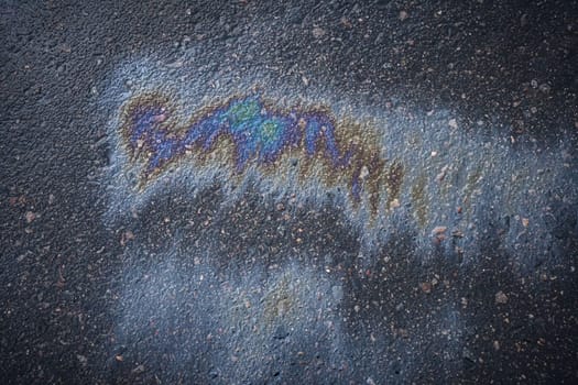 Gasoline spill showing iridescent colors on asphalt road.
