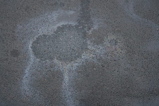 Colored texture of oil products on asphalt in bright sunlight after rain. Oil dripped from the car engine onto the road