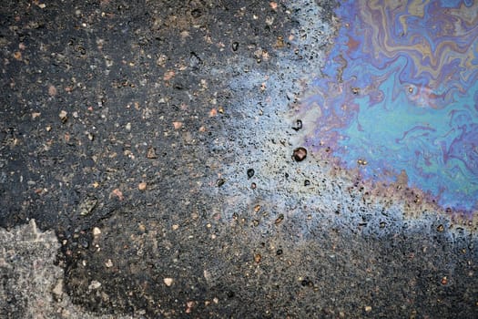 A top view of a shimmering film of oil or gasoline on wet pavement