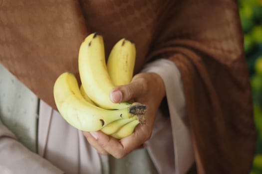 A person joyfully holding a bunch of ripe bananas amidst a vibrant and lively environment