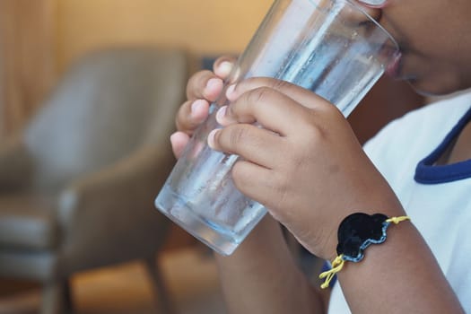 A joyful child happily enjoys a refreshing glass of clear, cool water on a sunny day