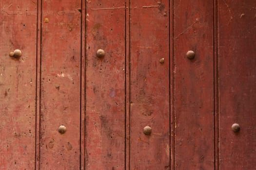 Texture of a wooden board painted red with rivets. Close-up.