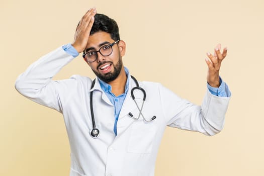 Indian young doctor cardiologist man feeling hopelessness and loneliness, nervous breakdown, loses, bad fortune, loss, unlucky news, fail. Arabian apothecary pharmacy guy isolated on beige background
