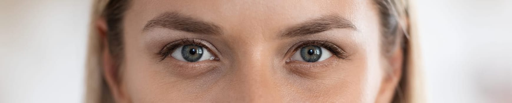 Beautiful eyes of caucasian millennial woman in her 30s, blurred background, web-banner, panorama with copy space for advertisement. Aesthetic medicine, plastic surgery, beauty treatment