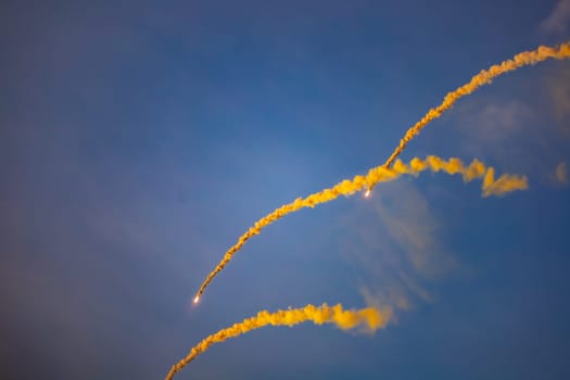 Beautifully glowing flares with a lot of smoke flying on the blue sky at golden hour before sunset