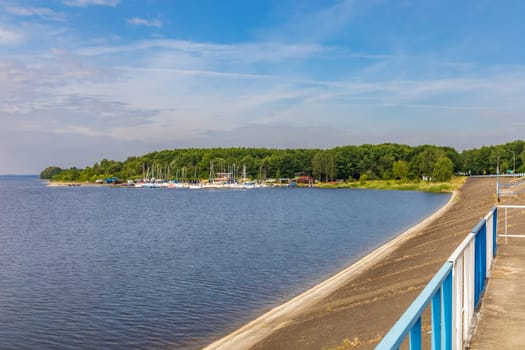 Small bay behind small local harbor at the coast of big lake next to water dame and road