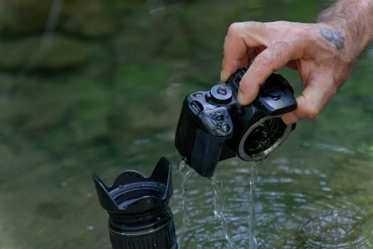 man pulls his digital camera out of the river that has accidentally fallen into the river flooded from inside