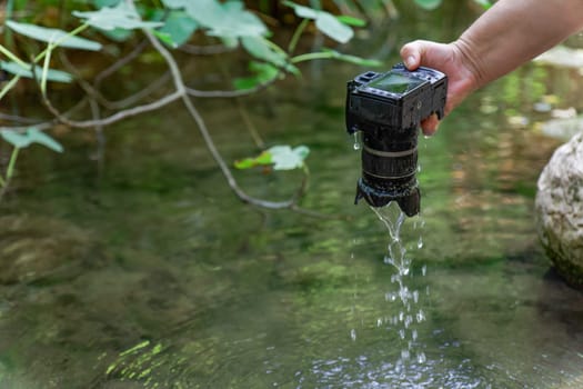 a reflex camera accidentally falls into the river, a man pulls it out of the water dripping wet.