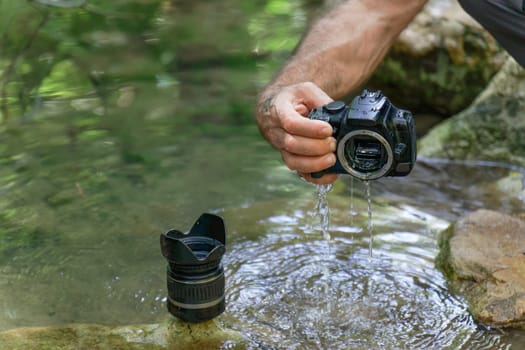 man pulls his digital camera out of the river that has accidentally fallen into the river flooded from inside