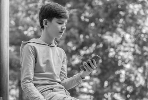 Teenager sitting outdoors with smartphone, copy space