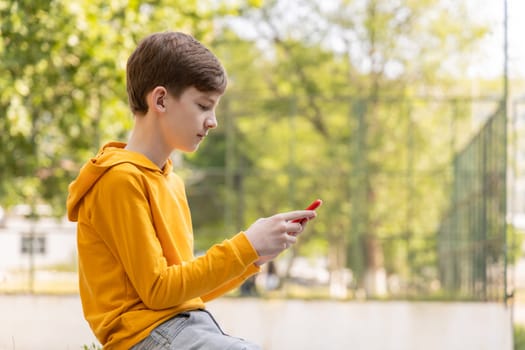 Teenager sitting outdoors with smartphone, copy space
