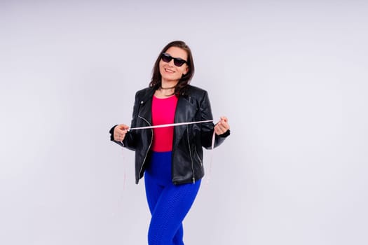 Overweight woman measuring waist before weight loss in a studio shot on yellow background