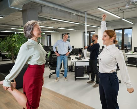 Four office workers warm up during a break. Employees do fitness exercises at the workplace