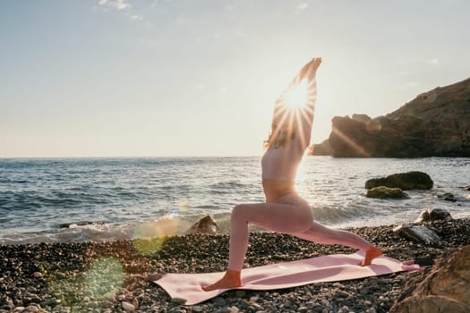 Young woman with black hair, fitness instructor in pink sports leggings and tops, doing pilates on yoga mat with magic pilates ring by the sea on the beach. Female fitness daily yoga concept