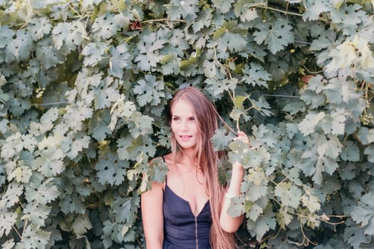 Woman at autumn winery. Portrait of happy woman holding glass of wine and enjoying in vineyard. Elegant young lady in hat toasting with wineglass smiling cheerfully enjoying her stay at vineyard