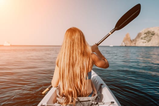 Woman in kayak back view. Happy young woman with long hair floating in transparent kayak on the crystal clear sea. Summer holiday vacation and cheerful female people relaxing having fun on the boat