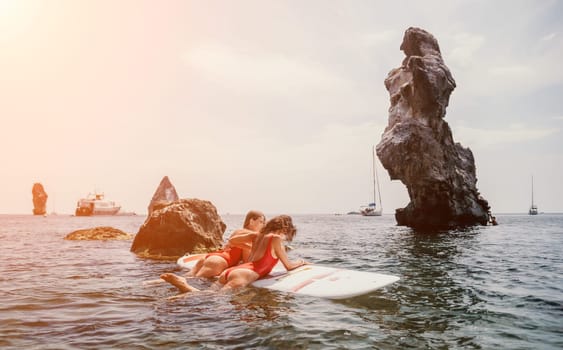 Woman sup yoga. Middle age sporty woman practising yoga pilates on paddle sup surfboard. Female stretching doing workout on sea water. Modern individual hipster outdoor summer sport activity