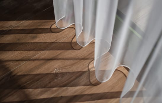Shadow from white curtains on wooden floor background. Quality laminate flooring concept