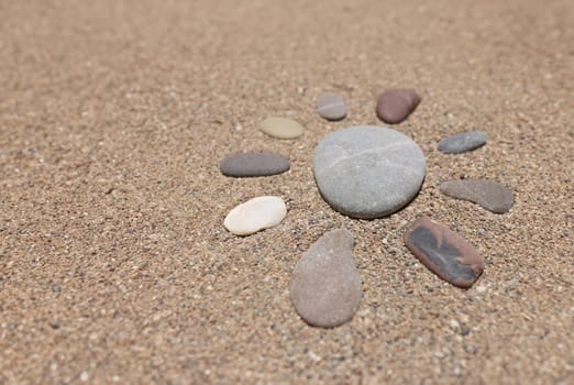 Figure of sun is made of pebble stones on sandy beach in summer. Travel tourism and holidays in warm countries