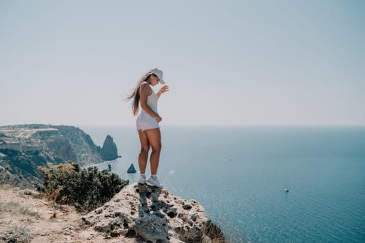 Woman travel sea. Young Happy woman in a long red dress posing on a beach near the sea on background of volcanic rocks, like in Iceland, sharing travel adventure journey