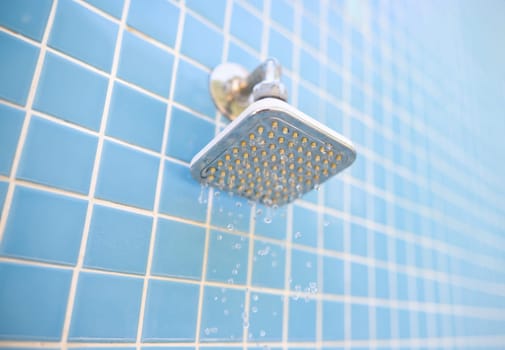 Wall-mounted outdoor shower and water drops on blue tile background. Summer showers for tourists in hotels