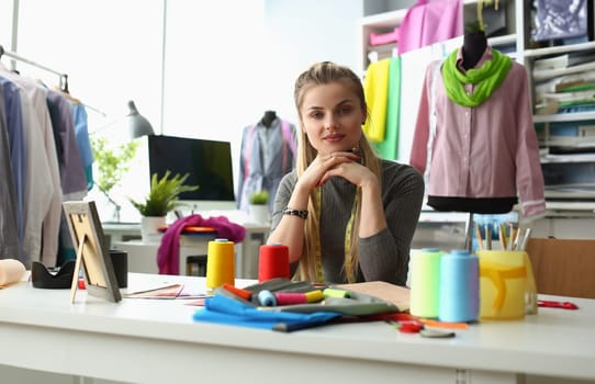 Portrait of smiling young dressmaker or tailor sewing fabric creates new clothes in own workshop. Happy designer or seamstress in fashion atelier