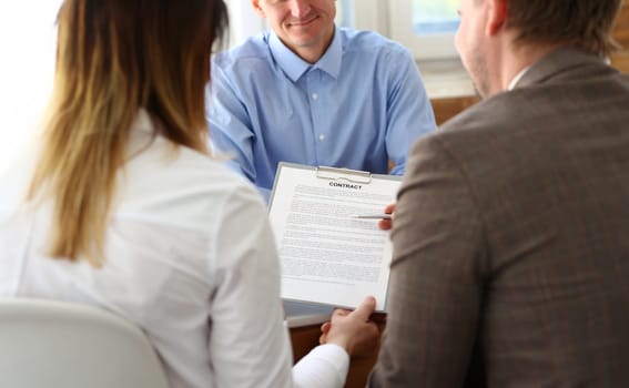 Married couple signs contract to buy house from male realtor or broker. Happy male and female customers signed an agreement with agent