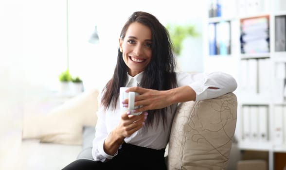 Portrait of smiling minded successful employee business woman in white shirt with cup. Concept of career achievement and rest in workplace