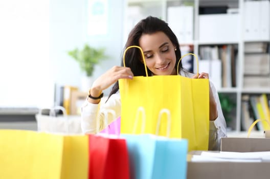 Beautiful woman is amazed to see gift in shopping bag. Concept of shopping and gifts