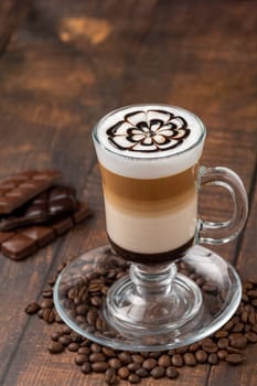 Multilayer coffee latte in glass cup on wooden table