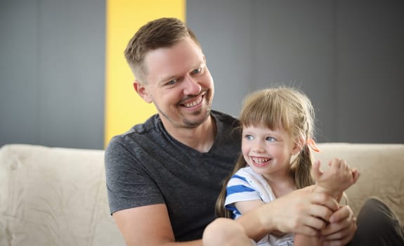 Happy dad holding cute cheerful daughter laughing and having good time together. Loving father and smiling little girl hugging and caring dad