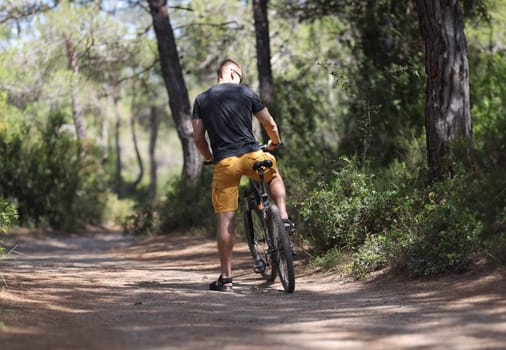 Ambitious man cyclist on forest path to sit on bicycle alone. Cycling enjoying nature in the forest