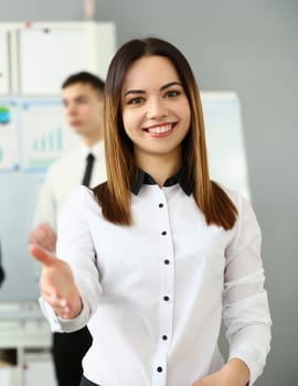 Smiling young business woman politely greets company office. Business consultant and team